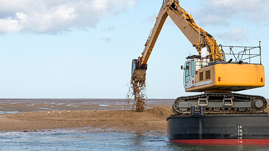 Excavator Dumping Sand Excavator in shallow waters moving sand